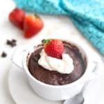 Keto Chocolate Protein Mug Cake in a white ramekin with whipped cream and a strawberry on top.