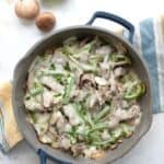 Top down image of Philly Cheesesteak Skillet in a blue pan over a striped napkin.