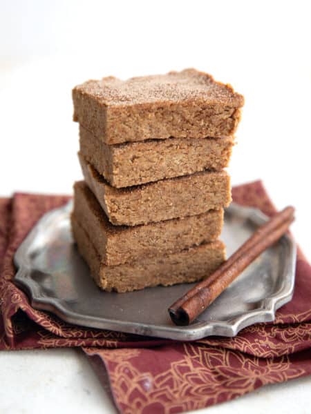 A stack of Snickerdoodle Protein Bars on a small pewter plate over a red and gold napkin.