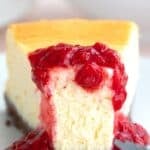 Titled image of a slice of Keto Air Fryer Cheesecake on a white plate with raspberry sauce, with a forkful taken out of it.