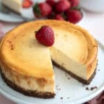 Air Fryer Keto Cheesecake on a white cake stand with a slice taken out of it.
