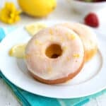 Close up shot of two keto lemon donuts on a white plate over a teal napkin.