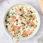 Top down image of Spinach Feta Chicken in a white enameled skillet on a marble tabletop.
