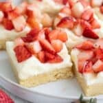 Titled image of Keto Strawberry Shortcake Bars arranged on a white plate on a white wooden table top.