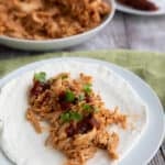 Keto BBQ Shredded Chicken on an egg white wrap on a white plate.