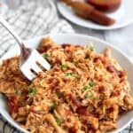 Keto BBQ Shredded Chicken piled up in a white bowl with a serving fork digging into it.