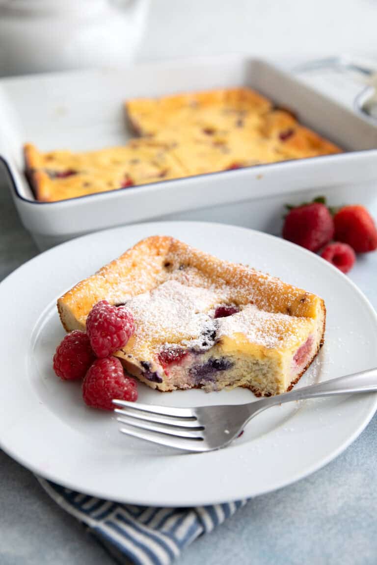 A slice of Keto Cottage Cheese Breakfast Bake with three raspberries and a fork on a white plate.