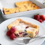A slice of Keto Cottage Cheese Breakfast Bake with three raspberries and a fork on a white plate.