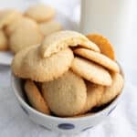 Keto Vanilla Wafers piled up in a bowl with one broken open on top.