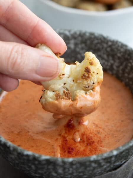 Close up shot of roasted cauliflower being dipped into keto comeback sauce.