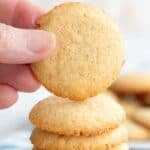 Titled image of hand holding up a keto vanilla wafer above a stack of more wafers.