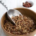 Keto Air Fryer Granola in a large brown ceramic bowl with a metal scoop digging into it.