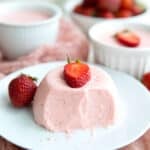 Keto Strawberry Panna Cotta on a white plate with several forkfuls taken out of it.
