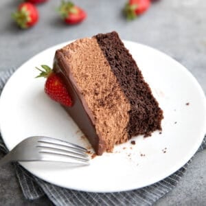 A slice of Keto Chocolate Mousse Cake on its side, on a white plate, with a forkful taken out of it.