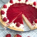 Keto Raspberry Cream Pie in a glass pie plate over a blue and white gingham napkin.