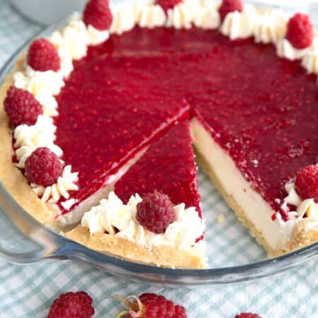 Keto Raspberry Cream Pie in a glass pie plate over a blue and white gingham napkin.