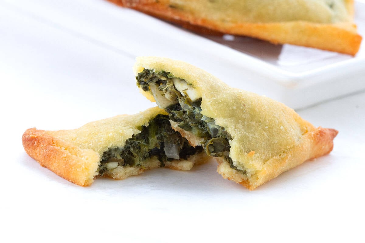 Close up shot of a keto spanakopita pastry broken open to show the filling inside.
