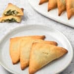 Three Keto Spanakopita arranged on a white plate, on a concrete table top.