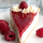 Close up shot of a slice of Keto Raspberry Cream Pie on a white plate with fresh raspberries.