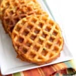 Cheddar zucchini waffles on a white rectangular platter over a striped napkin.