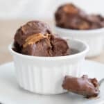 A white bowl with keto chocolate peanut butter ice cream, with a spoonful taken out of it.