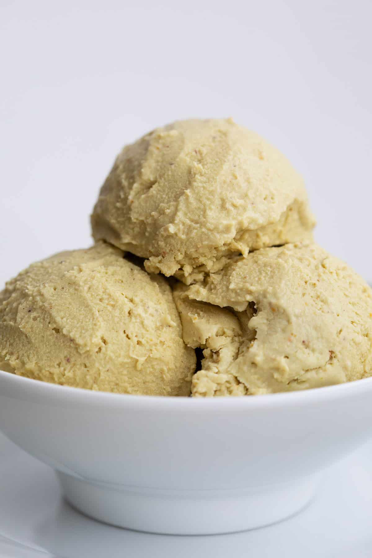 Close up shot of a white bowl with three scoops of keto pistachio ice cream.