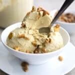A white bowl with three scoops of keto pistachio ice cream, with a spoon digging into it.