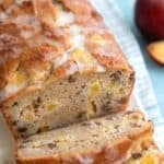 Titled image of a loaf of Keto Southern Peach Bread on a white and blue checked napkin with several slices cut out.