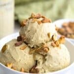 Titled image of A white bowl with three scoops of keto pistachio ice cream, topped with chopped, salted pistachios.
