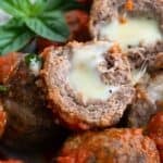 Titled image of keto stuffed meatballs piled up with one cut open to show the inside.