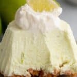Titled image of a mini frozen keto key lime pie on a small gray plate with several forkfuls taken out of it.