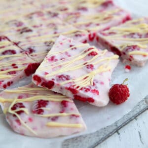 Squares of raspberry frozen yogurt bark on a cutting board covered with waxed paper.