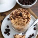 Tiramisu Protein Mousse in a glass dish with a spoonful taken out of it.