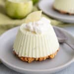 A Keto Frozen Key Lime Pie on a small gray plate with whipped cream and a lime slice on top.