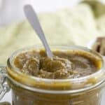 Titled image of keto pistachio cream in a glass jar with a spoon sticking out of it.