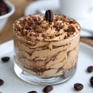 Close up shot of Tiramisu Protein Mousse in a glass dessert dish with chocolate shavings and an espresso bean on top.