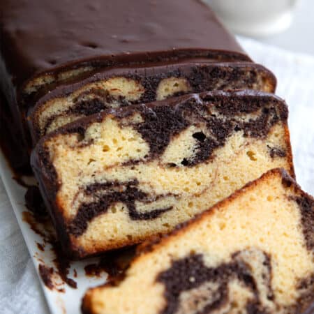 Keto Marble Pound Cake with chocolate glaze cut into slices on a white platter.