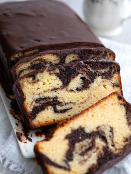 Keto Marble Pound Cake with chocolate glaze cut into slices on a white platter.