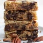 A stack of keto cookie bars loaded with chocolate on a white plate.