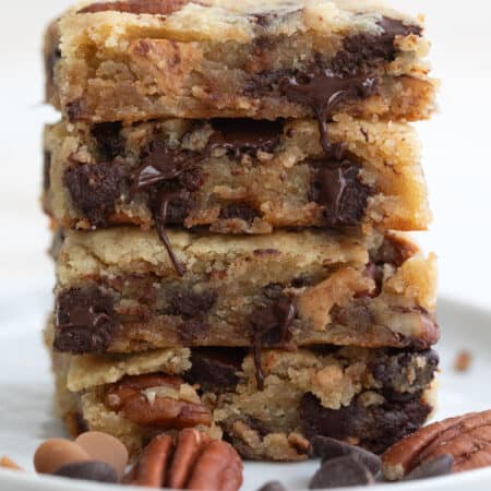 A stack of keto cookie bars loaded with chocolate on a white plate.
