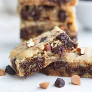Close up shot of a keto cookie bar with melty chocolate chips and chopped pecans.