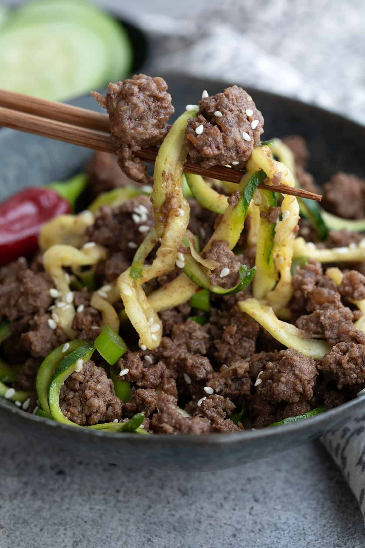 Close up photo of chopsticks holding up some Keto Korean Beef and zucchini noodles.