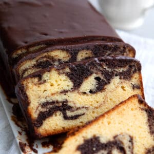 Keto Marble Pound Cake with chocolate glaze cut into slices on a white platter.