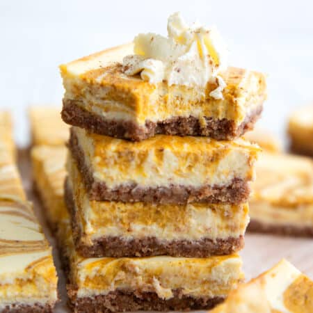 a stack of keto pumpkin cheesecake bars with a bite taken out of the top one.