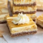 Close up shot of a keto pumpkin swirl cheesecake bar with a dollop of whipped cream on top.