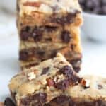 Two keto cookie bars leaned against each other on a white table top, with a stack of more bars in behind.
