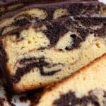 Titled image of Keto Marble Pound Cake with chocolate glaze cut into slices on a white platter.