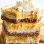 Titled image of a stack of keto pumpkin cheesecake bars with a bite taken out of the top one.