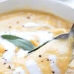 Titled image close up of a spoon digging into a bowl of Creamy Keto Pumpkin Soup.