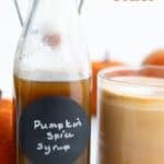 Titled image of a bottle of Keto Pumpkin Spice Syrup beside a cup of coffee with frothed milk.